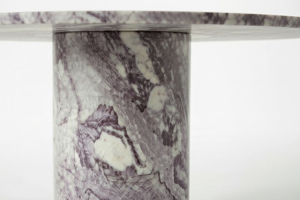 Close-up of a round marble table top and matching cylindrical pedestal base, featuring a white and gray stone surface with prominent purple veining.