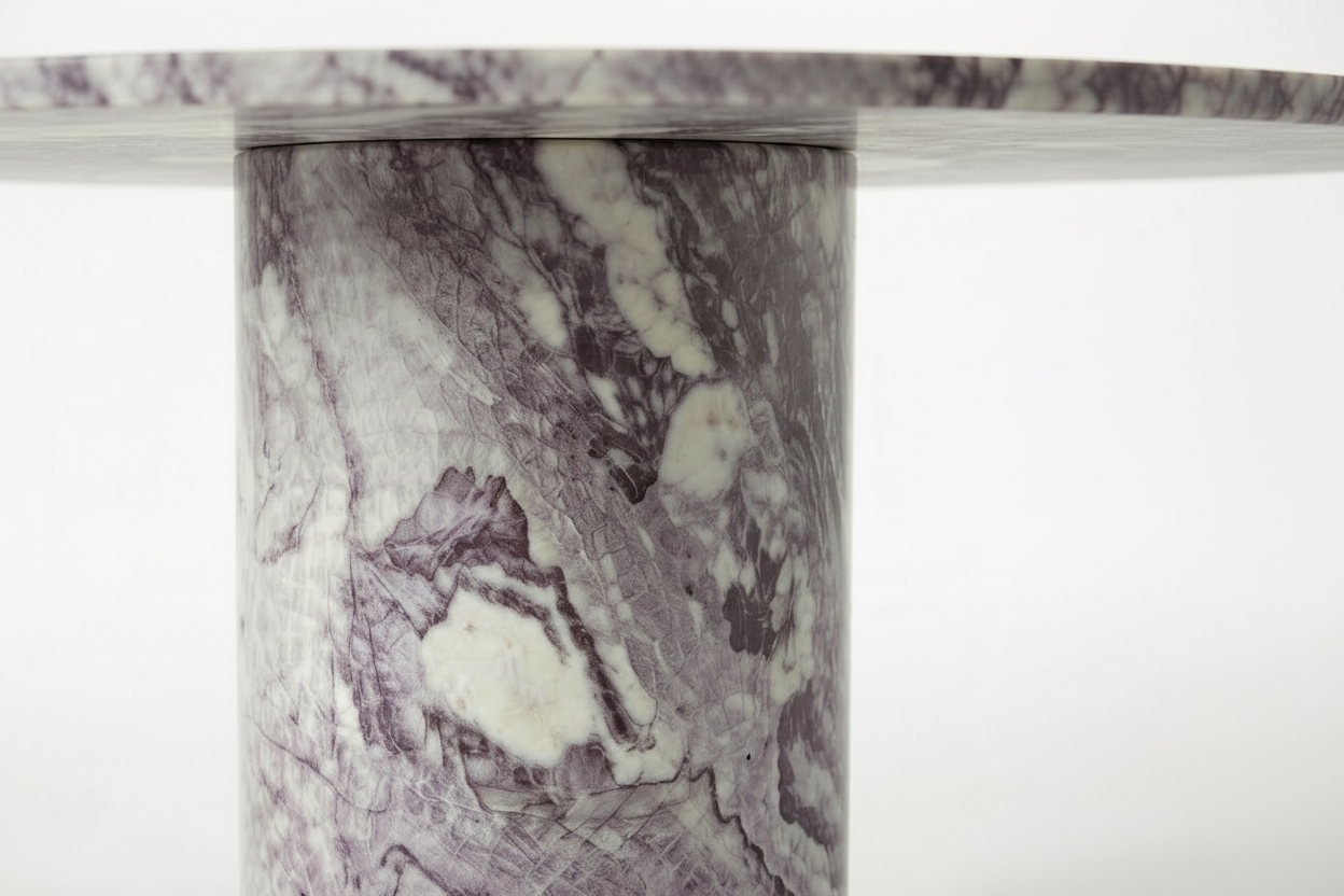 Close-up of a round marble table top and matching cylindrical pedestal base, featuring a white and gray stone surface with prominent purple veining.